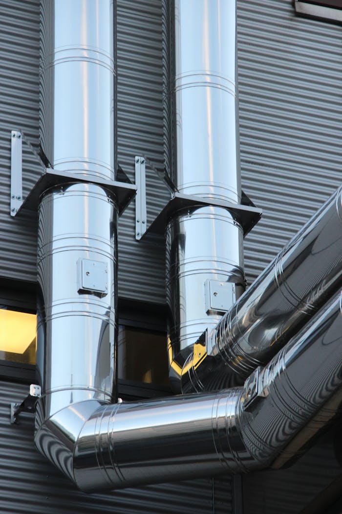 Home Close-up of shiny stainless steel pipes on an industrial building facade, showcasing modern technology.